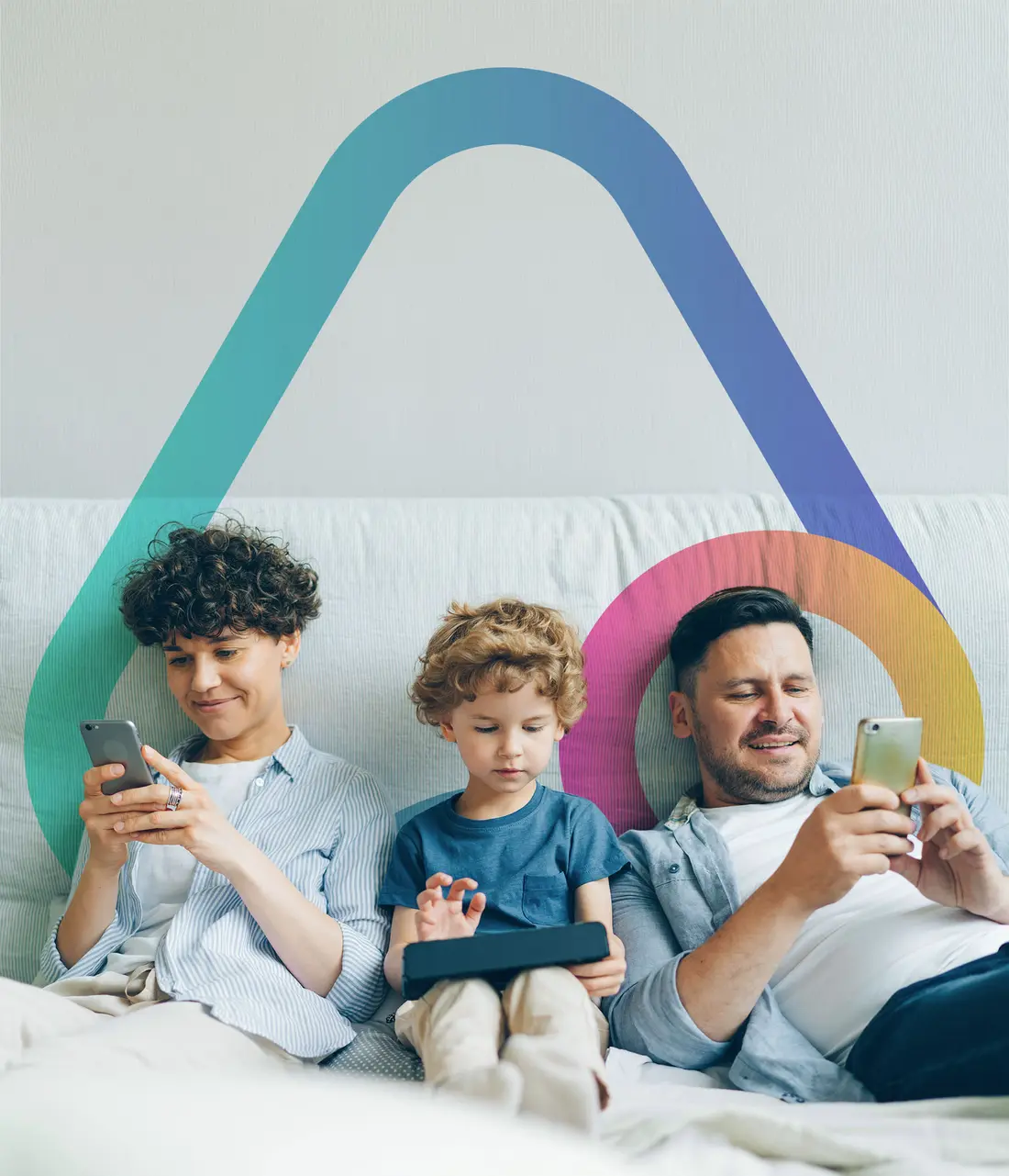 A mother, father and their young child relaxing together on a couch using their devices